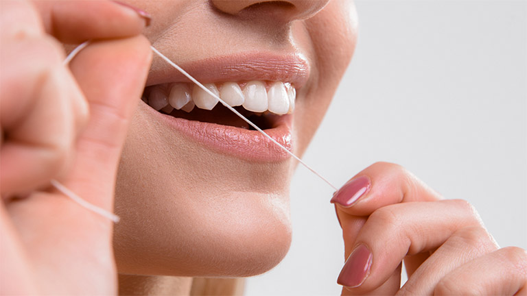 Sử dụng chỉ nha khoa để loại bỏ thức ăn dư thừa trong kẽ răng thay vì sử dụng tăm tre